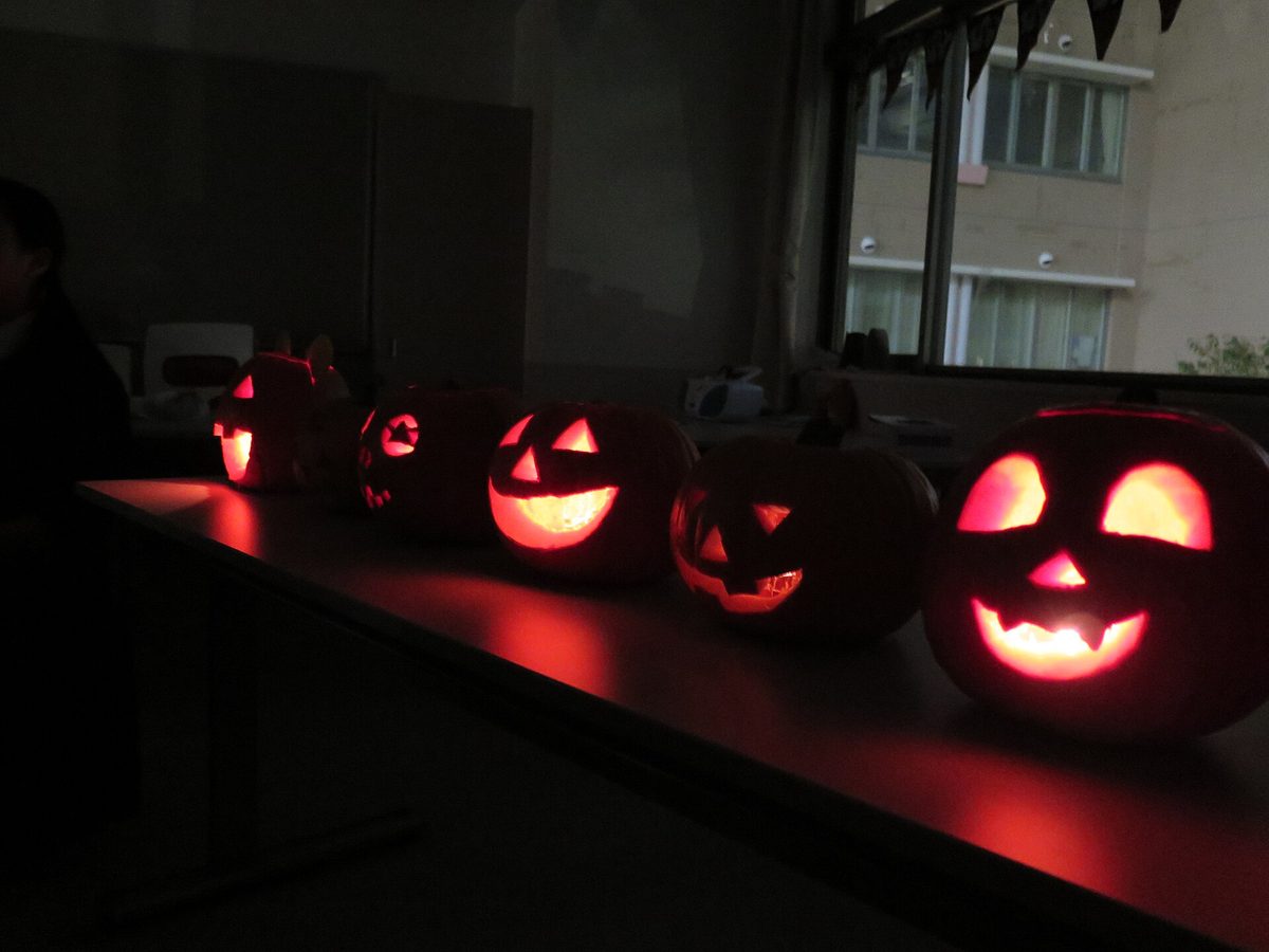 Five carved jack-o-lanterns glowing on a table at night